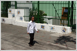 Man walking past tiled wall.