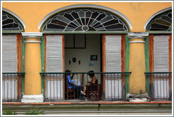 Family sitting near an open window, Plaza de Armas, Old Havana.