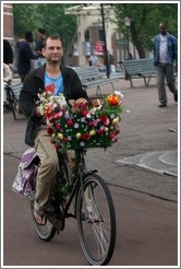 Man on bicycle with flowers and dogs.