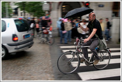 Bicyclist holding umbrella.  Dam Square, Centrum district.