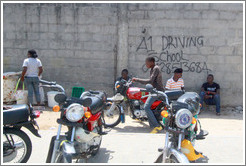 Kids and motorcycles in front of A1 Driving School written on a wall. Victoria Island.
