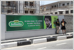Man and woman speaking in front of a billboard, Maroko Road, Victoria Island.