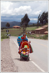Woman walking with a baby in a stroller along the road near the Puca Pucara ruins.