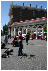 Street performer with one arm and two instruments.  Saturday Market.